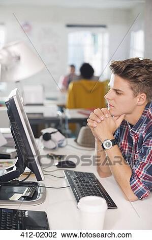 Stock Image - Businessman working at computer at desk. Fotosearch