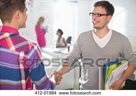 Picture - Businessmen shaking hands in office. Fotosearch