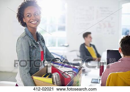 Stock Image - Businesswoman carrying cardboard box of belongings. Fotosearch