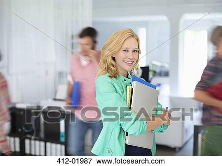 Stock Photo - Businesswoman carrying folders in office. Fotosearch