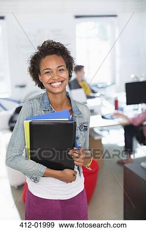 Businesswoman carrying folders in office View Large Photo Image Stock Photo - Businesswoman carrying folders in office. Fotosearch