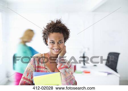 Stock Photo - Businesswoman carrying folders in office. Fotosearch