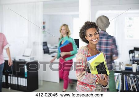 Stock Photography - Businesswoman carrying folders in office. Fotosearch