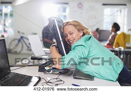 Stock Photograph - Businesswoman hugging computer at desk. Fotosearch