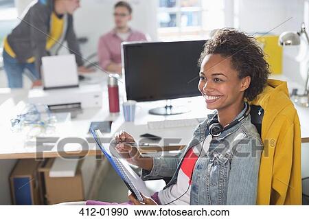 Stock Image - Businesswoman making notes at desk. Fotosearch