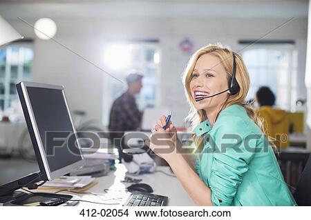 Picture - Businesswoman talking on headset at desk. Fotosearch