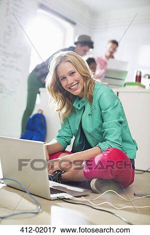 Stock Photo - Businesswoman using laptop on floor in office. Fotosearch