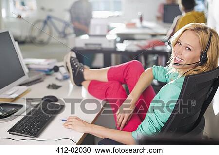 Businesswoman wearing headset at desk View Large Photo Image Stock Image - Businesswoman wearing headset at desk. Fotosearch