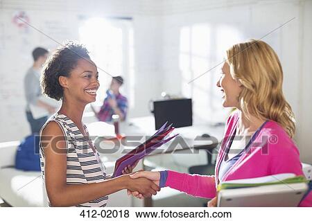 Businesswomen shaking hands in office View Large Photo Image Stock Photo - Businesswomen shaking hands in office. Fotosearch