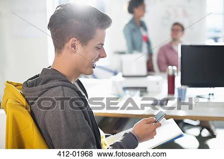 Man using cell phone in office View Large Photo Image Stock Photo - Man using cell phone in office. Fotosearch