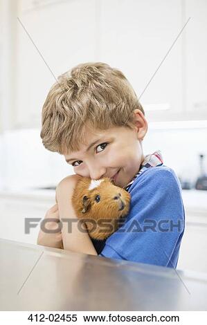Boy cuddling guinea pig in vet's surgery View Large Photo Image Stock Photography - Boy cuddling guinea pig in vet's surgery. Fotosearch