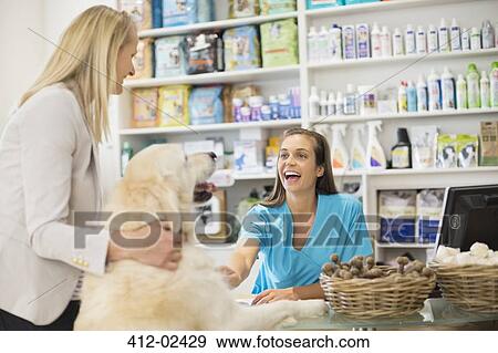 Receptionist greeting dog in vet's surgery View Large Photo Image Stock Photo - Receptionist greeting dog in vet's surgery. Fotosearch