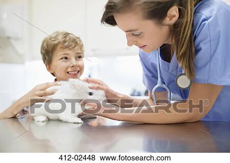 Stock Photo - Vet examining rabbit with boy. Fotosearch