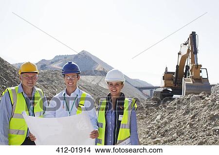 Business people reading blueprints in quarry View Large Photo Image Picture - Business people reading blueprints in quarry. Fotosearch