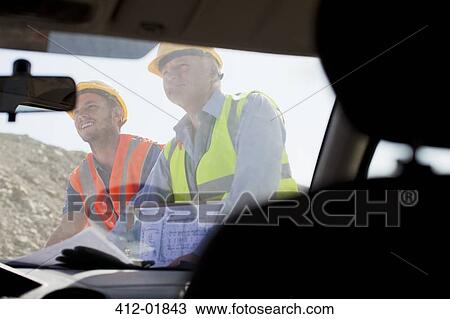 Businessman and worker reading blueprints on site View Large Photo Image Stock Image - Businessman and worker reading blueprints on site. Fotosearch