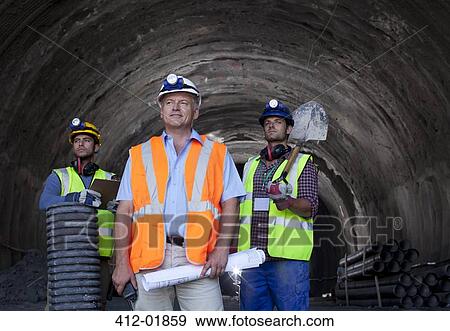 Stock Photo - Businessman and workers standing in tunnel. Fotosearch