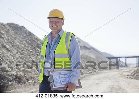 Businessman carrying clipboard in quarry View Large Photo Image Stock Photography - Businessman carrying clipboard in quarry. Fotosearch