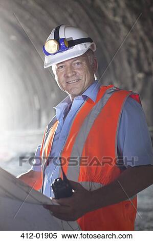 Businessman reading blueprints in tunnel View Large Photo Image Stock Photography - Businessman reading blueprints in tunnel. Fotosearch