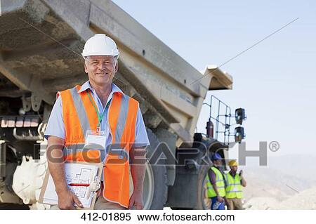 Businessman standing by truck on site View Large Photo Image Stock Photography - Businessman standing by truck on site. Fotosearch