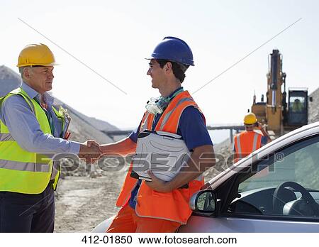 Stock Image - Worker and businessman shaking hands in quarry. Fotosearch