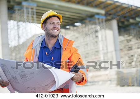 Worker reading blueprints on site View Large Photo Image Stock Image - Worker reading blueprints on site. Fotosearch