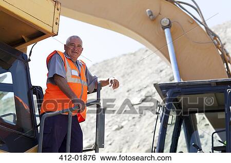 Worker standing on machinery on site View Large Photo Image Stock Photograph - Worker standing on machinery on site. Fotosearch