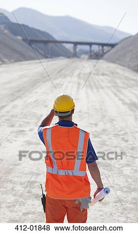 Worker standing on road in quarry View Large Photo Image Stock Photo - Worker standing on road in quarry. Fotosearch
