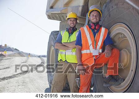 Workers leaning on machinery on site View Large Photo Image Stock Photograph - Workers leaning on machinery on site. Fotosearch