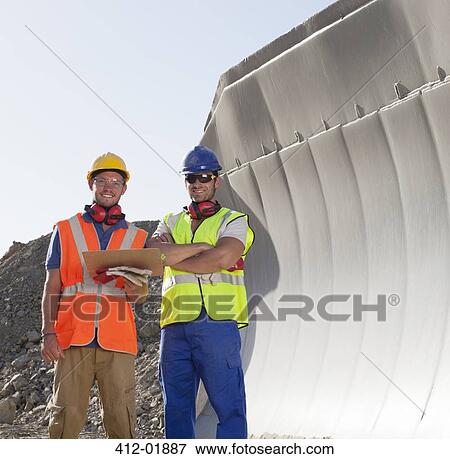 Workers smiling by machinery in quarry View Large Photo Image Stock Photo - Workers smiling by machinery in quarry. Fotosearch