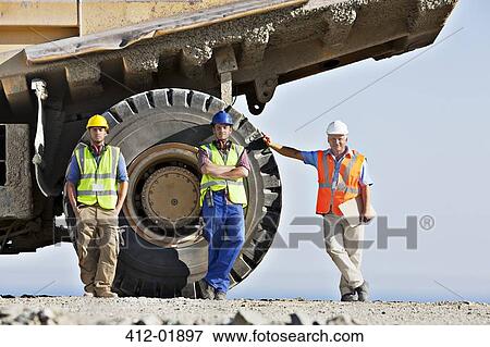 Workers standing by machinery on site View Large Photo Image Stock Photo - Workers standing by machinery on site. Fotosearch