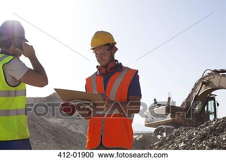 Stock Image - Workers standing in quarry. Fotosearch