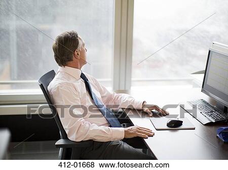 Businessman gazing out window in office View Large Photo Image Stock Photo - Businessman gazing out window in office. Fotosearch