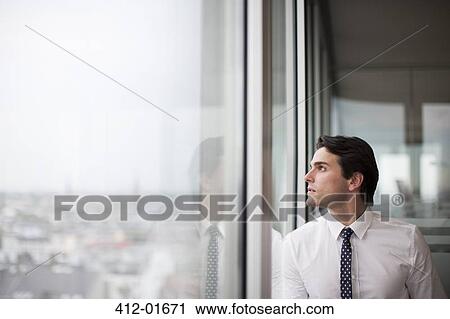 Businessman looking out office window View Large Photo Image Stock Image - Businessman looking out office window. Fotosearch