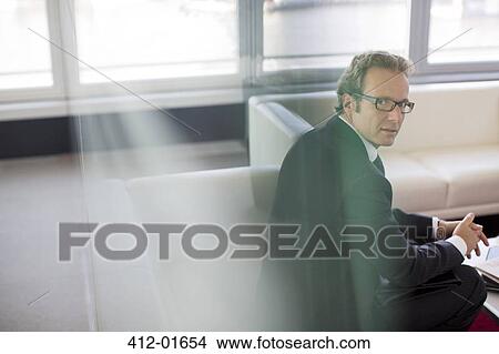 Picture - Businessman sitting in office lobby area. Fotosearch