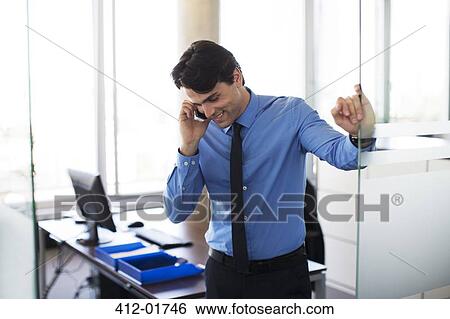 Businessman talking on cell phone in office View Large Photo Image Stock Photograph - Businessman talking on cell phone in office. Fotosearch