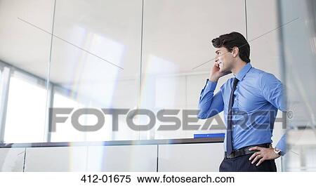Businessman talking on cell phone in office View Large Photo Image Stock Photography - Businessman talking on cell phone in office. Fotosearch