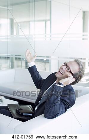 Businessman talking on cell phone on sofa View Large Photo Image Stock Photo - Businessman talking on cell phone on sofa. Fotosearch