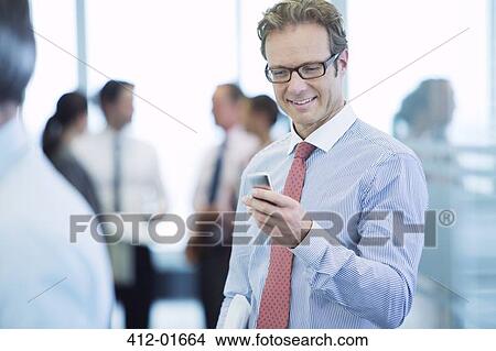 Picture - Businessman using cell phone in office. Fotosearch