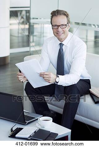 Businessman working in office lobby View Large Photo Image Stock Photo - Businessman working in office lobby. Fotosearch