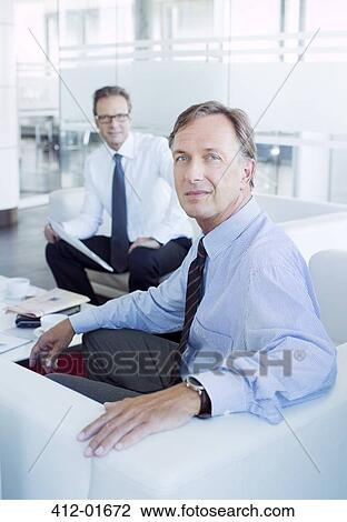 Businessmen sitting in office lobby area View Large Photo Image Stock Image - Businessmen sitting in office lobby area. Fotosearch