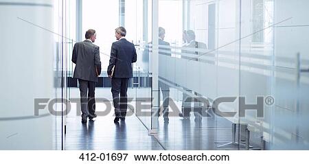 Stock Photo - Businessmen talking in office hallway. Fotosearch