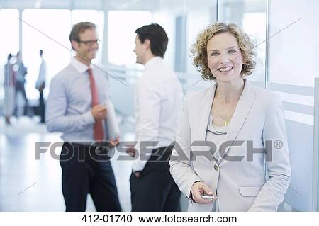 Businesswoman smiling in office hallway View Large Photo Image Stock Image - Businesswoman smiling in office hallway. Fotosearch
