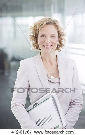Businesswoman smiling in office hallway View Large Photo Image Stock Photo - Businesswoman smiling in office hallway. Fotosearch