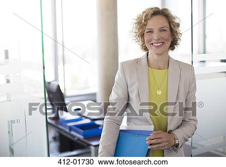 Stock Image - Businesswoman smiling in office. Fotosearch