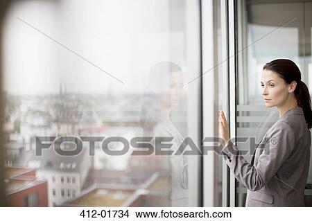 Businesswoman standing at office window View Large Photo Image Picture - Businesswoman standing at office window. Fotosearch