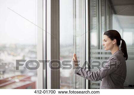 Businesswoman standing at office window View Large Photo Image Stock Image - Businesswoman standing at office window. Fotosearch