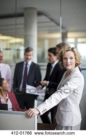 Businesswoman standing by cubicle in office View Large Photo Image Stock Photograph - Businesswoman standing by cubicle in office. Fotosearch
