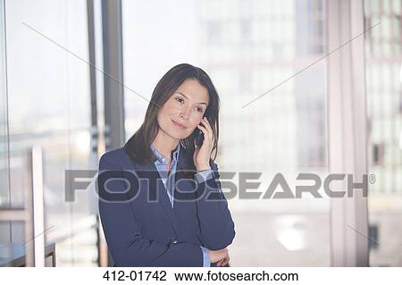 Businesswoman talking on cell phone in office View Large Photo Image Stock Image - Businesswoman talking on cell phone in office. Fotosearch