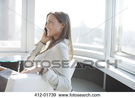 Stock Photo - Businesswoman talking on phone in office. Fotosearch