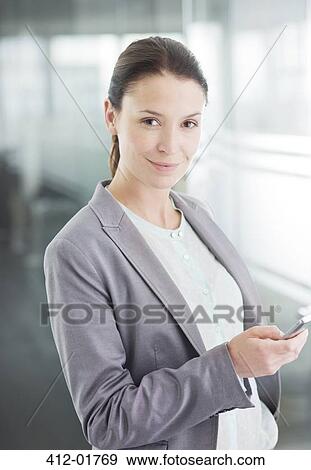 Businesswoman using cell phone in office View Large Photo Image Stock Photo - Businesswoman using cell phone in office. Fotosearch